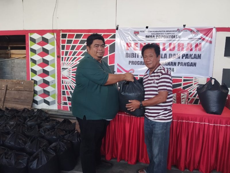 Hukum Tua Ferry Pangala saat menyalurkan bibit ikan dan pakan kepada salah seorang warga Desa Popontolen